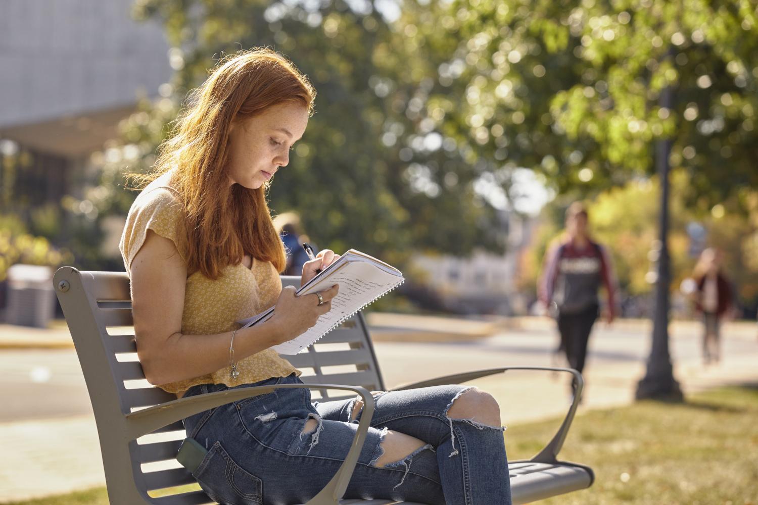A <a href='http://rtz3x.fontinagrup.com'>BETVLCTOR伟德登录</a> student reads on a bench along Campus Drive.